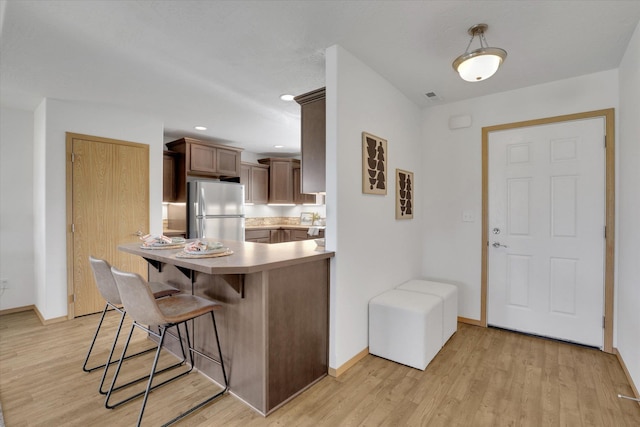 1002 N Oasis Ave, Deer Park, WA 99006 - kitchen with freestanding refrigerator, a breakfast bar area, and light wood-style floors