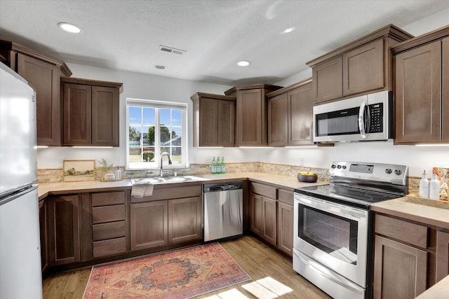 1002 N Oasis Ave, Deer Park, WA 99006 - kitchen featuring appliances with stainless steel finishes, a sink, light countertops, light wood finished floors, and recessed lighting
