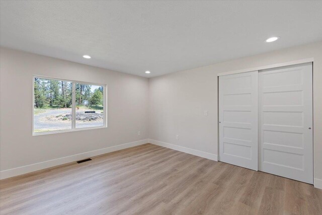 12510 N Craig Rd, Nine Mile Falls, WA 99026 - unfurnished bedroom with light wood-type flooring, recessed lighting, baseboards, and a closet