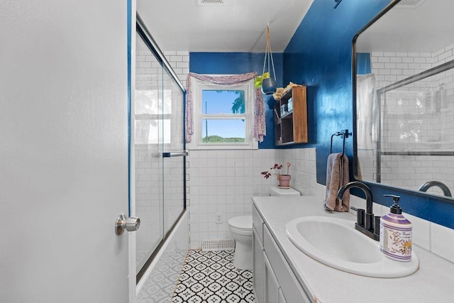 611 E Mill St, Latah, WA 99018 - bathroom with toilet, vanity, bath / shower combo with glass door, and tile walls