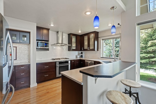 526 W Willapa Ct, Spokane, WA 99224 - kitchen featuring appliances with stainless steel finishes, wall chimney range hood, a sink, a peninsula, and a breakfast bar