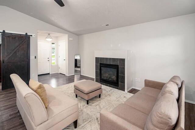 704 E Canterbury Ln, Colbert, WA 99005 - living room featuring dark wood-style flooring, lofted ceiling, a barn door, baseboards, and a tile fireplace