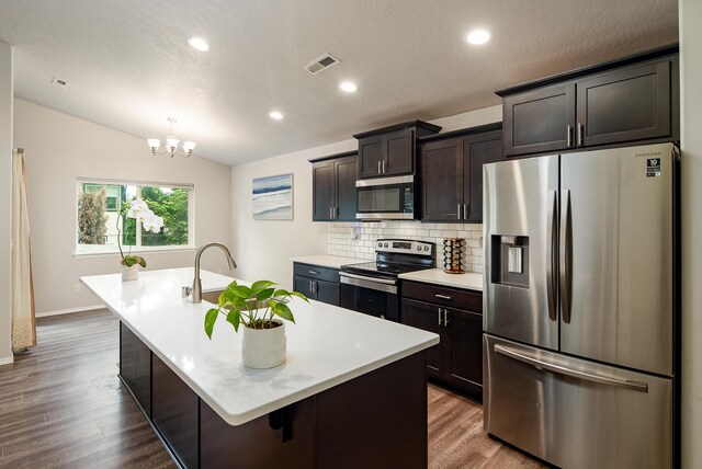 704 E Canterbury Ln, Colbert, WA 99005 - kitchen with appliances with stainless steel finishes, wood finished floors, a kitchen island with sink, decorative backsplash, and light countertops