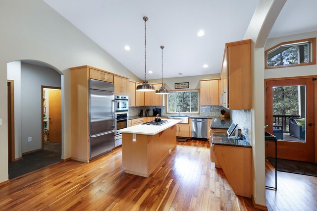 13906 E 39th Ln, Veradale, WA 99037 - kitchen with appliances with stainless steel finishes, a center island, arched walkways, light wood-type flooring, and backsplash