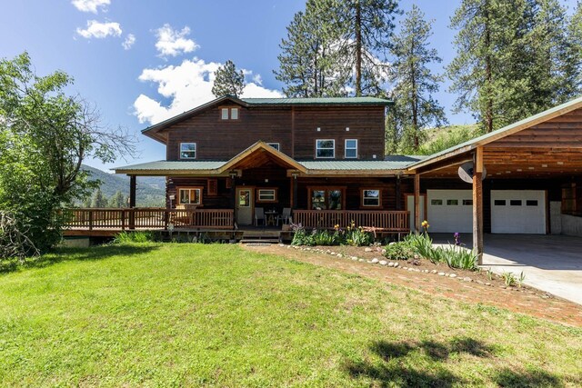3439 B Northport Flat Creek Rd, Kettle Falls, WA 99141 - view of front of property with an attached garage, a front lawn, concrete driveway, covered porch, and metal roof