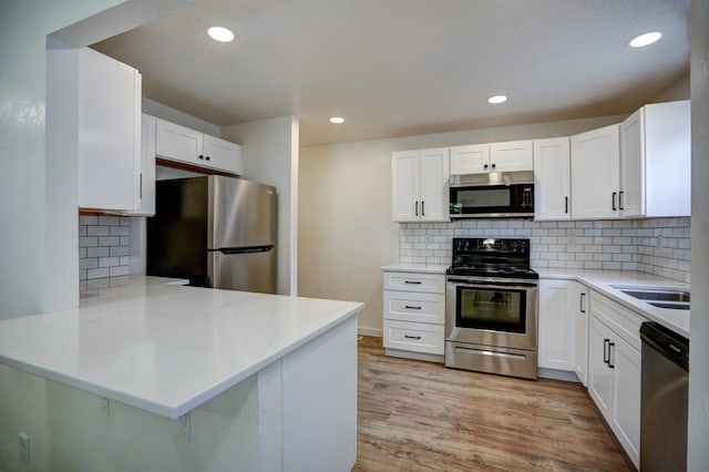 5320 N Ash St, Spokane, WA 99205 - kitchen with appliances with stainless steel finishes, a peninsula, light countertops, decorative backsplash, and white cabinetry