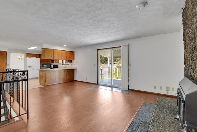 11619 N Roundup Rd, Mead, WA 99021 - unfurnished living room with a textured ceiling, light wood-style flooring, baseboards, and a chandelier