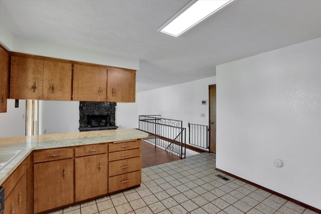 11619 N Roundup Rd, Mead, WA 99021 - kitchen with light countertops, brown cabinetry, a fireplace, and baseboards