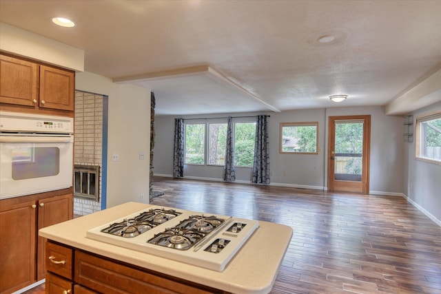 1815 E 64th Ave, Spokane, WA 99223 - kitchen featuring white appliances, brown cabinets, open floor plan, light countertops, and dark wood finished floors