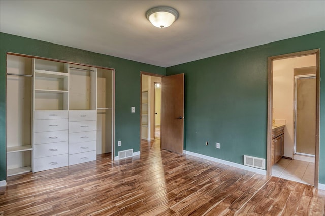 1815 E 64th Ave, Spokane, WA 99223 - unfurnished bedroom featuring wood finished floors, a closet, baseboards, and ensuite bath