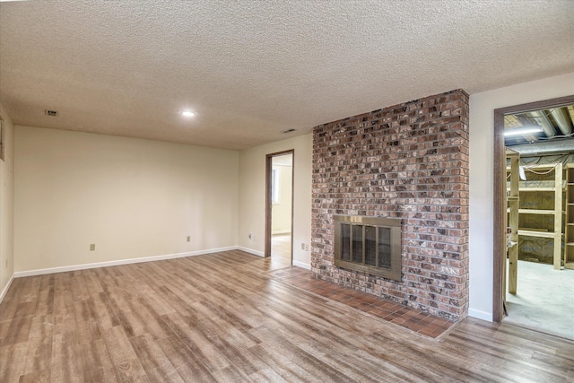 1815 E 64th Ave, Spokane, WA 99223 - unfurnished living room with wood finished floors, a brick fireplace, a textured ceiling, baseboards, and recessed lighting