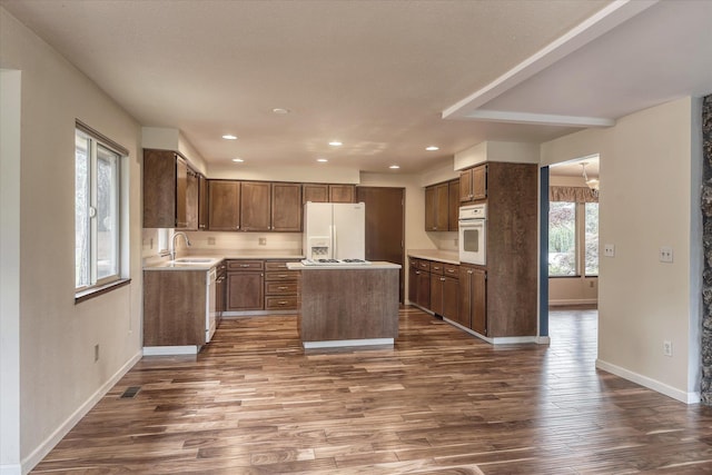 1815 E 64th Ave, Spokane, WA 99223 - kitchen with white appliances, dark wood-style floors, a sink, baseboards, and a center island