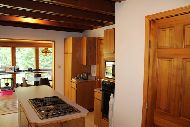 42604 Hatch Rd, Deer Park, WA 99006 - kitchen with black oven, stovetop with downdraft, brown cabinetry, beam ceiling, and stainless steel microwave