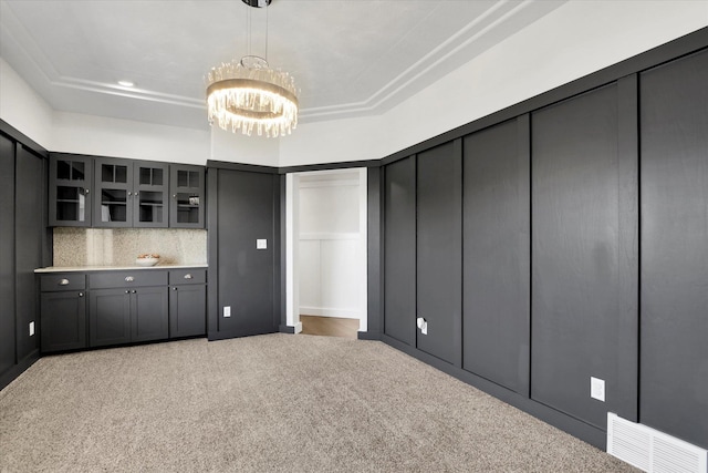 2306 W Rainier Ct, Spokane, WA 99208 - interior space with a chandelier, carpet, glass insert cabinets, tasteful backsplash, and light countertops