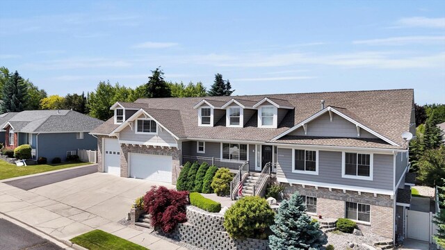 2306 W Rainier Ct, Spokane, WA 99208 - view of front of home featuring driveway, stone siding, a garage, covered porch, and stairway