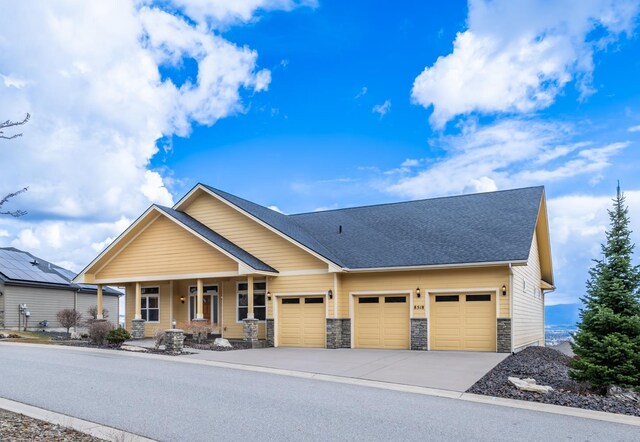 8518 E Black Oak Ln, Spokane, WA 99217 - craftsman house featuring a porch, a garage, concrete driveway, stone siding, and a shingled roof