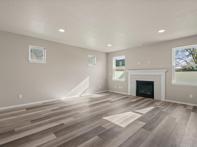 5112 N Silas Ln Unit 9/1Talent, Spokane Valley, WA 99216 - unfurnished living room featuring light wood-style floors, baseboards, a glass covered fireplace, recessed lighting, and a textured ceiling