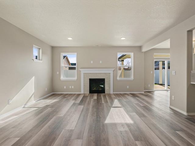5112 N Silas Ln Unit 9/1Talent, Spokane Valley, WA 99216 - unfurnished living room featuring wood finished floors, baseboards, a textured ceiling, a brick fireplace, and recessed lighting