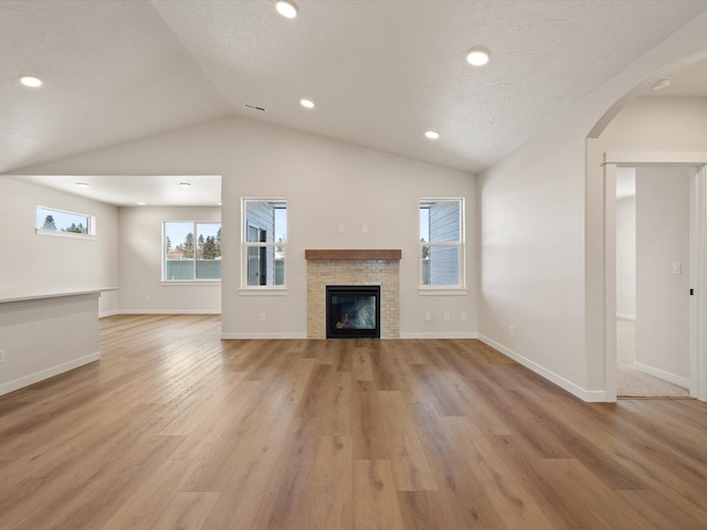 1438 W 67th Ave Lot 5Block 3, Orchard, Spokane, WA 99224 - unfurnished living room featuring vaulted ceiling, light wood finished floors, arched walkways, a stone fireplace, and baseboards