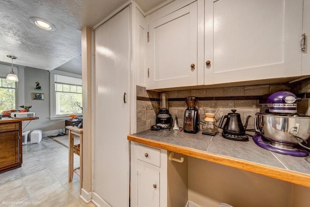 1611 W 9th Ave, Spokane, WA 99223 - kitchen with white cabinetry, backsplash, a textured ceiling, baseboards, and a desk