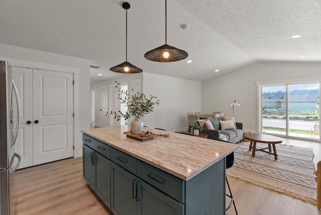 14101 E Sanson Ave, Spokane Valley, WA 99216 - kitchen with light wood finished floors, stainless steel fridge, lofted ceiling, a center island, and decorative light fixtures