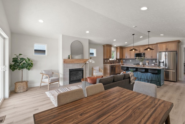 14101 E Sanson Ave, Spokane Valley, WA 99216 - dining space with light wood-style flooring, lofted ceiling, recessed lighting, baseboards, and a fireplace