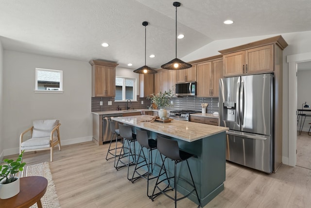 14101 E Sanson Ave, Spokane Valley, WA 99216 - kitchen featuring appliances with stainless steel finishes, light wood-style floors, decorative backsplash, a kitchen breakfast bar, and baseboards