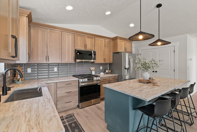 14101 E Sanson Ave, Spokane Valley, WA 99216 - kitchen featuring appliances with stainless steel finishes, a sink, lofted ceiling, light wood finished floors, and a kitchen bar