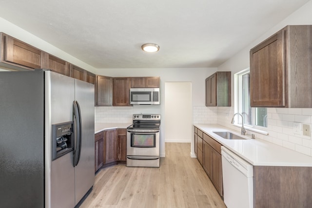 624 N Herald Rd Unit 2, Spokane Valley, WA 99206 - kitchen featuring appliances with stainless steel finishes, a sink, light wood-style floors, tasteful backsplash, and light countertops