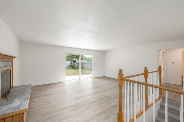 624 N Herald Rd Unit 2, Spokane Valley, WA 99206 - unfurnished living room featuring a fireplace with raised hearth, light wood finished floors, baseboards, and a textured ceiling