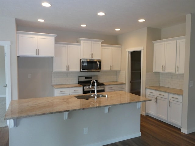 3223 S Custer Ln, Spokane, WA 99223 - kitchen with stainless steel appliances, a sink, white cabinets, dark wood-type flooring, and a center island with sink