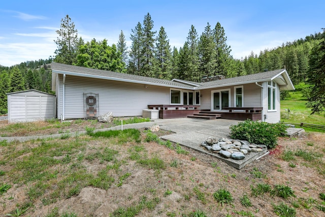 128C Buena Vista Rd, Colville, WA 99114 - rear view of house featuring a patio area, a forest view, and an outbuilding