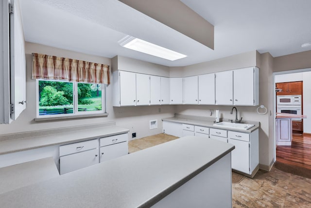 128C Buena Vista Rd, Colville, WA 99114 - kitchen featuring a sink, white appliances, white cabinetry, light countertops, and baseboards