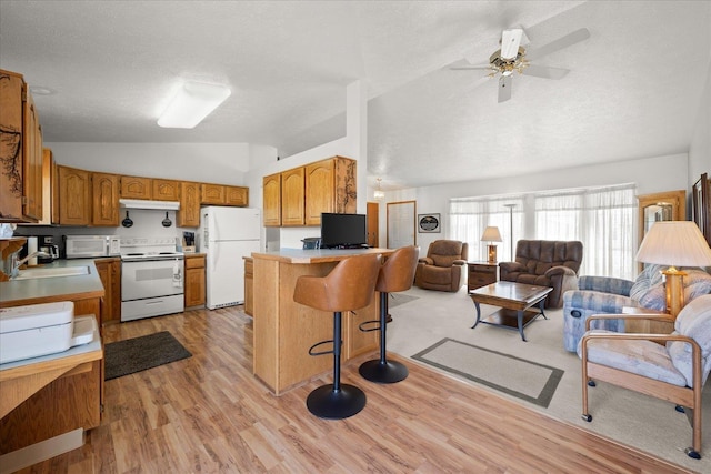 13715 E Rich Ave, Spokane Valley, WA 99216 - kitchen featuring white appliances, lofted ceiling, a sink, a peninsula, and light wood-style flooring
