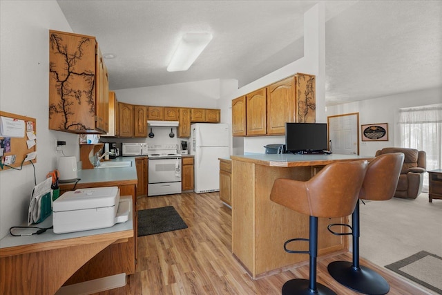 13715 E Rich Ave, Spokane Valley, WA 99216 - kitchen with white appliances, a sink, vaulted ceiling, brown cabinets, and a peninsula