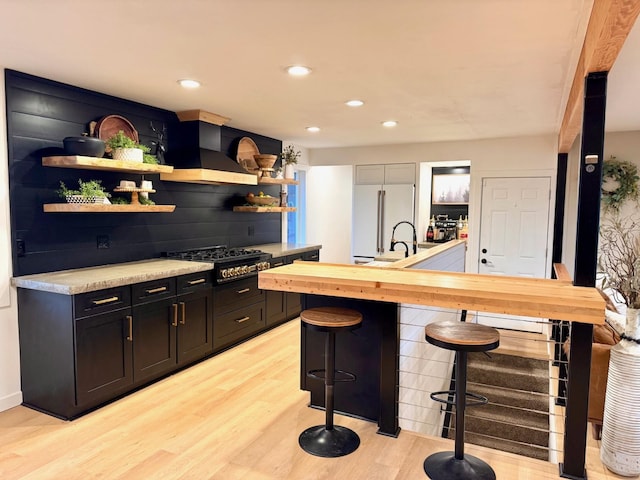 8616 E Desmet Ave, Spokane Valley, WA 99212 - kitchen with custom range hood, stovetop, white fridge, open shelves, and light wood-style floors