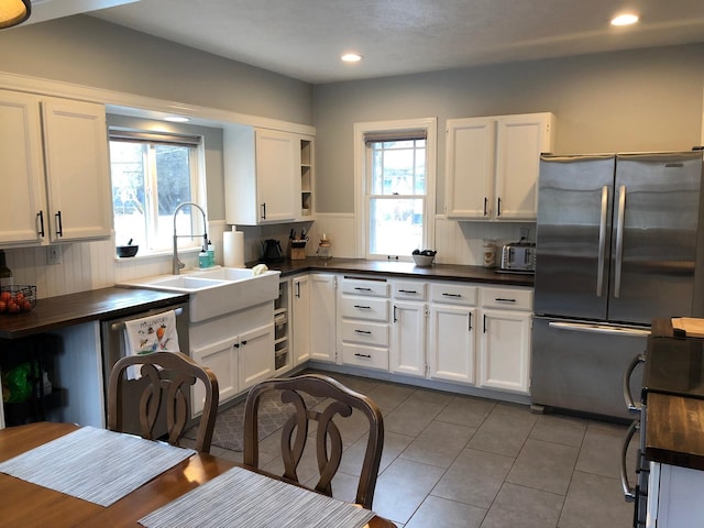 1617 S Bernard St, Spokane, WA 99203 - kitchen featuring dark countertops, appliances with stainless steel finishes, a sink, open shelves, and plenty of natural light