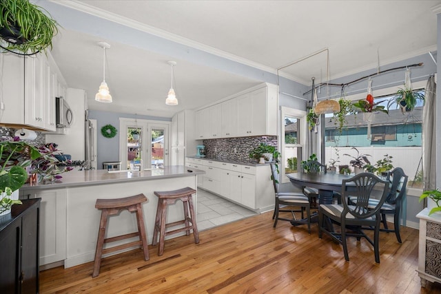 1306 W Euclid Ave, Spokane, WA 99205 - kitchen with stainless steel microwave, a peninsula, white cabinets, decorative backsplash, and light wood finished floors