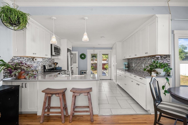 1306 W Euclid Ave, Spokane, WA 99205 - kitchen featuring stainless steel appliances, a peninsula, white cabinets, and backsplash
