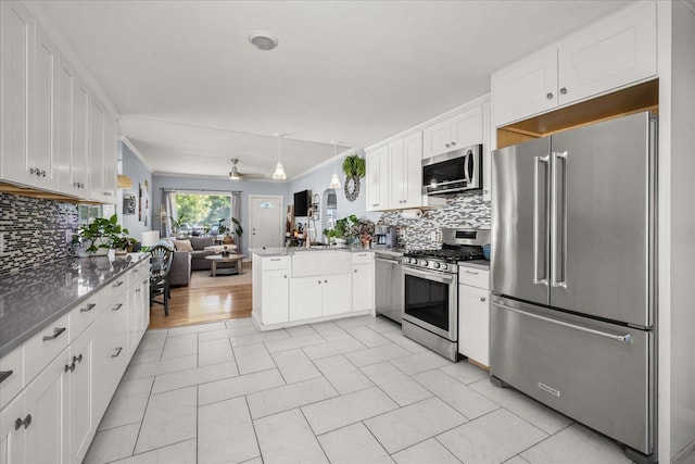 1306 W Euclid Ave, Spokane, WA 99205 - kitchen with appliances with stainless steel finishes, open floor plan, a peninsula, decorative backsplash, and white cabinets