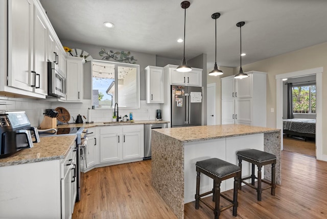 1812 E Columbia Ave, Spokane, WA 99208 - kitchen with appliances with stainless steel finishes, a sink, light wood-style floors, backsplash, and white cabinetry