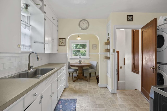 967 E 13th Ave, Spokane, WA 99202 - kitchen featuring a sink, estacked washer and dryer, white cabinetry, decorative backsplash, and light countertops