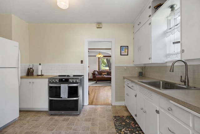 967 E 13th Ave, Spokane, WA 99202 - kitchen with range with two ovens, freestanding refrigerator, a sink, white cabinets, and decorative backsplash