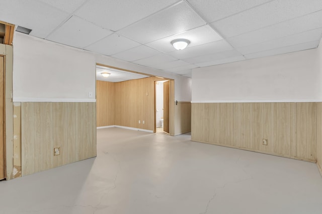 3228 E 29th Ave, Spokane, WA 99223 - unfurnished room with wooden walls, finished concrete flooring, a paneled ceiling, and a wainscoted wall