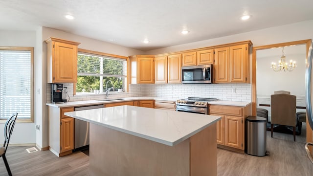 6314 W Skagit Ave, Spokane, WA 99208 - kitchen featuring stainless steel appliances, a sink, light wood-style floors, a chandelier, and decorative backsplash