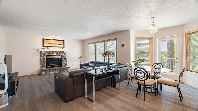 6314 W Skagit Ave, Spokane, WA 99208 - living area featuring a textured ceiling, wood finished floors, baseboards, a chandelier, and a stone fireplace