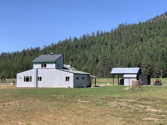2694B Sand Canyon Rd, Chewelah, WA 99109 - view of grassy yard featuring a wooded view, an outbuilding, and an outdoor structure