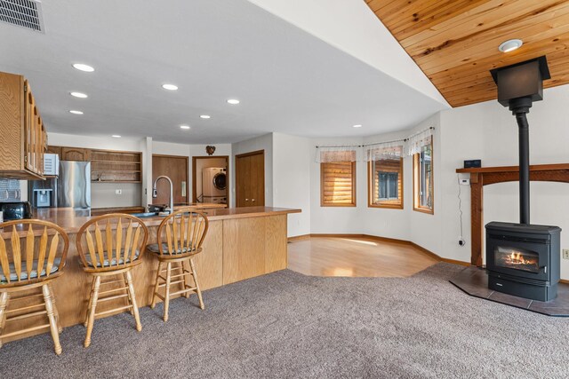 2378 Eagle River Way, Kettle Falls, WA 99141 - kitchen featuring recessed lighting, a wood stove, light carpet, vaulted ceiling, and stainless steel fridge with ice dispenser