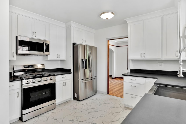 411 W 26th Ave, Spokane, WA 99203 - kitchen with appliances with stainless steel finishes, light marble finish floors, white cabinets, and dark countertops