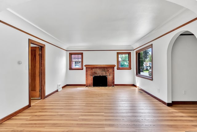 411 W 26th Ave, Spokane, WA 99203 - unfurnished living room with a fireplace, light wood-type flooring, arched walkways, ornamental molding, and baseboards